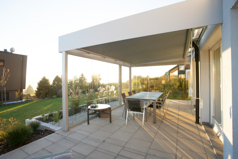 Pergola avec rideaux de verre, offrant un espace extérieur lumineux, protégé et utilisable toute l’année.